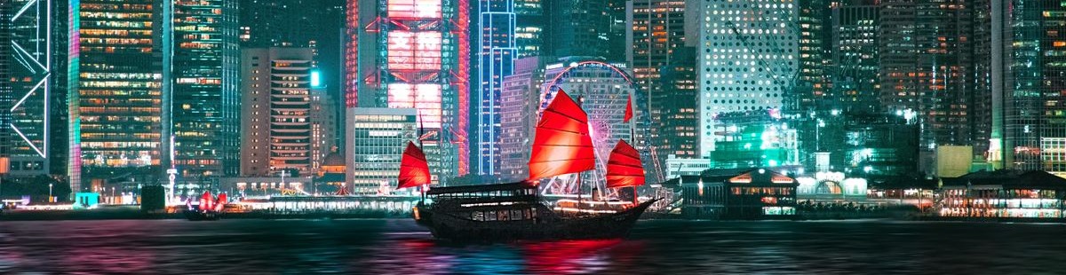 Traditional junk boat with red sails on Hong Kong harbour at night